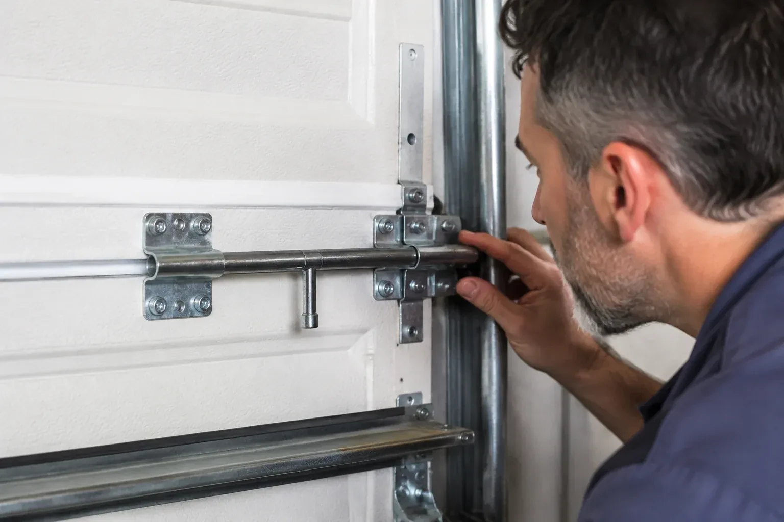Person leaning close to a white paneled door, one hand on a metal slide-bolt bar mounted across the panel. — Garage Door Manual Lock Repair, Toronto